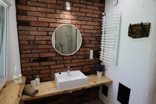 a bathroom with a white sink and a brick wall at Słońce i cień in Baligród