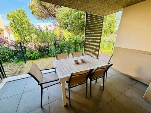 une table et des chaises sur une terrasse avec une grande fenêtre dans l'établissement Nice apartment with garden direct access to beach,Parking free, à Vias