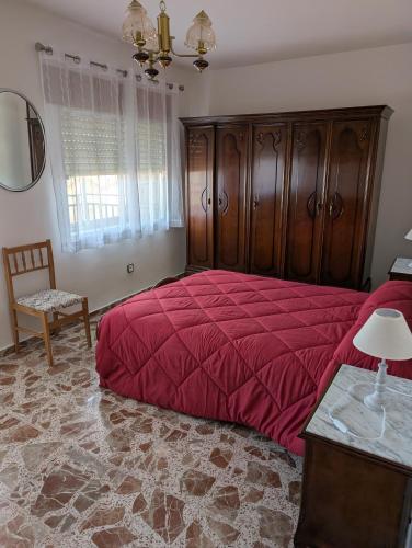 a bedroom with a large red bed and a chair at la erilla vieja in Navarrevisca