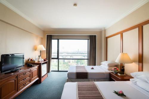 a hotel room with two beds and a flat screen tv at Bangkok Palace Hotel in Bangkok