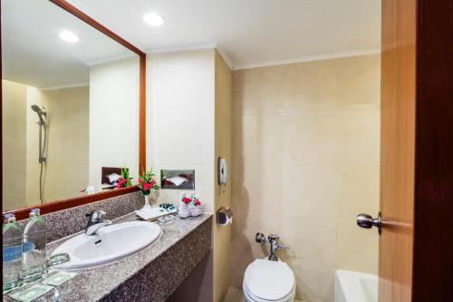 a bathroom with a sink and a toilet and a mirror at Bangkok Palace Hotel in Bangkok