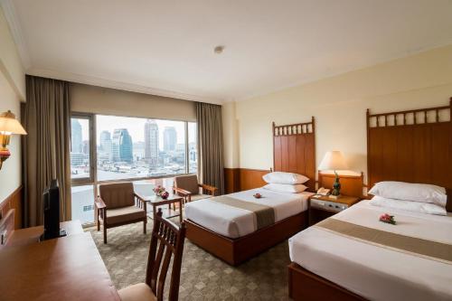a hotel room with two beds and a large window at Bangkok Palace Hotel in Bangkok