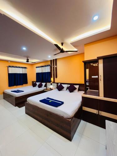 two beds in a room with yellow walls at Hotel Holiday Home in Digha