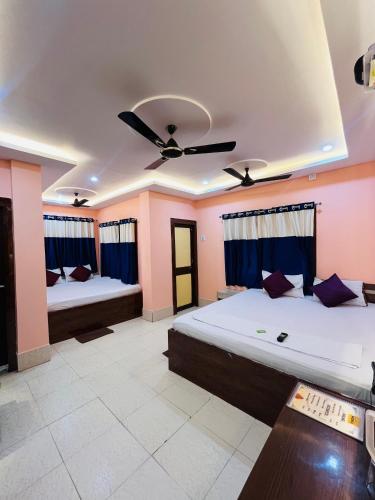 a bedroom with two beds and a ceiling fan at Hotel Holiday Home in Digha