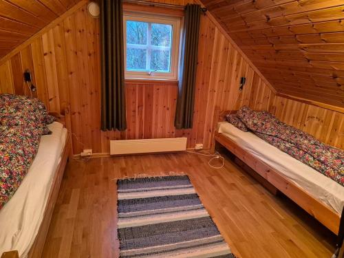 a room with two beds in a wooden cabin at Roligheten hytte in Farsund