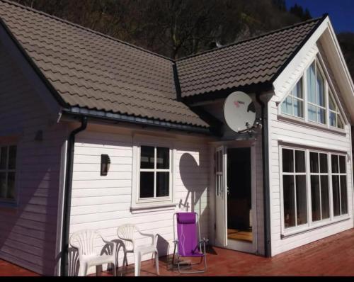a small white house with chairs and a purple chair at Roligheten hytte in Farsund