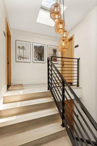 a hallway with stairs and a chandelier at Tide House - Unit D - Modern Oceanview 1BD w Parking in El Segundo