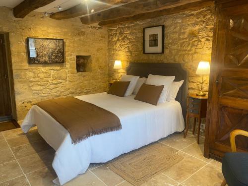 une chambre avec un grand lit dans un mur de pierre dans l'établissement Le Clos des hirondelles, à Veyrignac