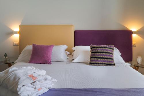 a bed with purple and white pillows on it at Kepos Etna Relais & Exclusive Spa in Santa Venerina