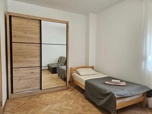 a small bedroom with a mirror and a bed at Apartman Palma in Kumbor