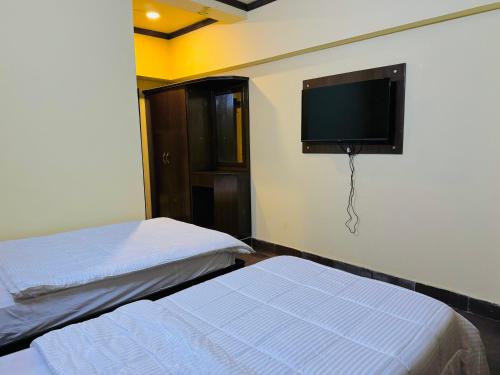 a room with two beds and a flat screen tv at Al Makkah Hotel in Karachi