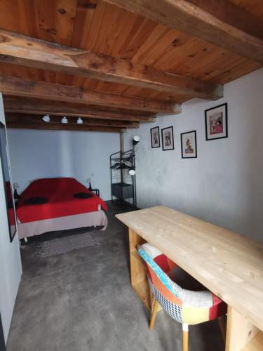 une chambre avec un lit rouge et une table en bois dans l'établissement Duplex à inaugurer, à Florac