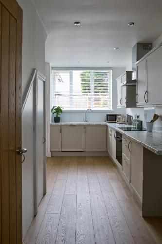a kitchen with white cabinets and a large window at Cosy Nook - 3 Bedroom Retreat with Private Garden, Parking and Media Wall in Belle Isle