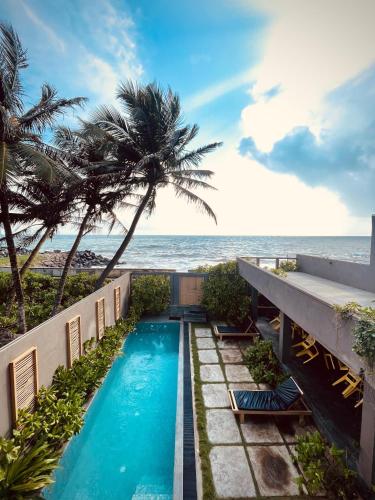 a swimming pool next to the beach with a palm tree at Villa Sea Queen in Ambalangoda