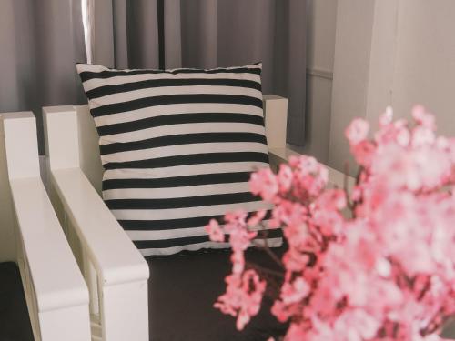a black and white pillow and a white chair and pink flowers at Boxsoon Nimman 2 # 4beds 3baths in Chiang Mai