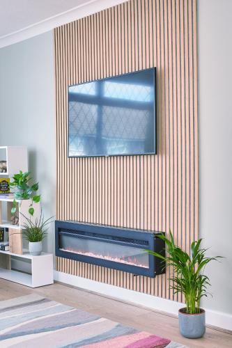a living room with a tv hanging on a wall at Cosy Nook - 3 Bedroom Retreat with Private Garden, Parking and Media Wall in Belle Isle