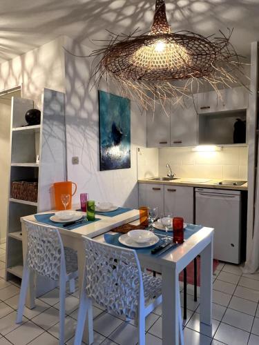 d'une cuisine avec une table blanche, des chaises et un éclairage. dans l'établissement F2 Cabine Terrasse Plage à pied 4 pers LGM, à La Grande Motte