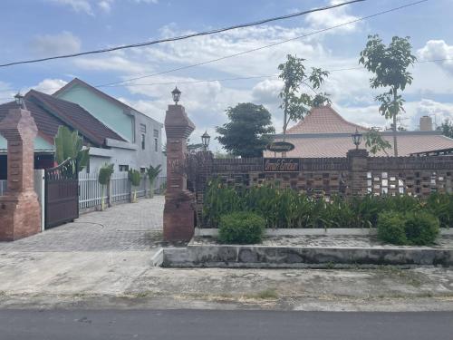a brick fence with a gate in front of a house at Homestay Omah Embun in Godean