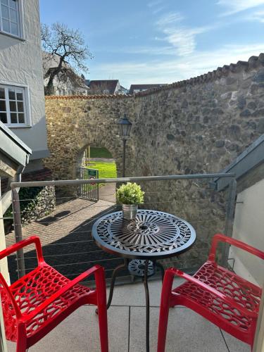 a patio with two red chairs and a table on a balcony at Ferienwohnung Stadtgarten in Radolfzell am Bodensee