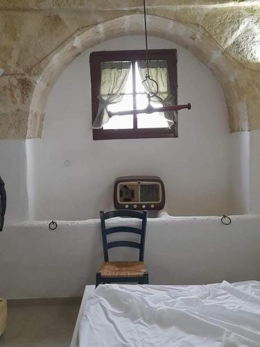 a bedroom with a bed and a window and a chair at Masseria Le Mesolecchie in Crispiano
