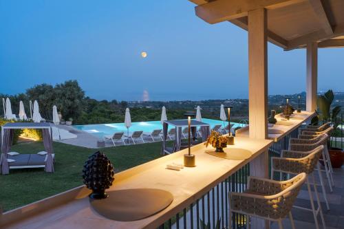 a row of tables and chairs on a balcony with a pool at Kepos Etna Relais & Exclusive Spa in Santa Venerina