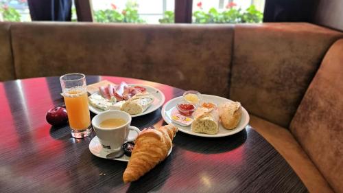 a table with two plates of breakfast food and orange juice at Hôtel de la Poste in Gedinne