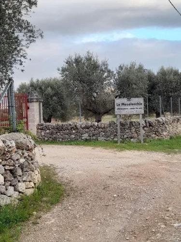 a sign on a road next to a stone wall at Masseria Le Mesolecchie in Crispiano