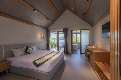 a bedroom with a bed and a desk and a balcony at Phu Ninh Lake Resort & Spa in Tam Ky