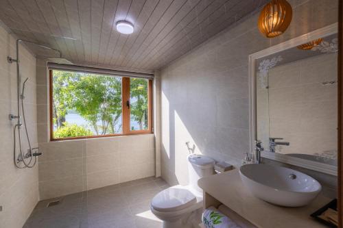 a bathroom with a sink and a toilet and a window at Phu Ninh Lake Resort & Spa in Tam Ky