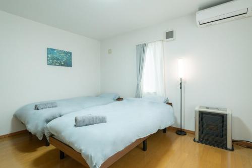 Dos camas en una habitación blanca con ventana. en Kikusui House, en Sapporo
