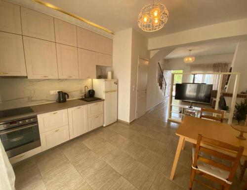 a kitchen with white cabinets and a table and a dining room at Maisonette Mara in Kriopigi