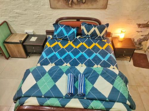 a bed with a blue and white comforter and pillows at Ivory Room, AC, Smart TV, Ensuite, Independent Homestay in Mumbai