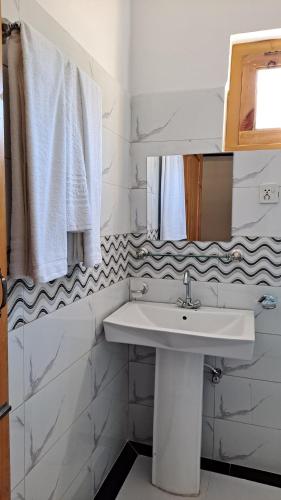 un bagno bianco con lavandino e specchio di Adventure Sarai Hotel Skardu a Skardu