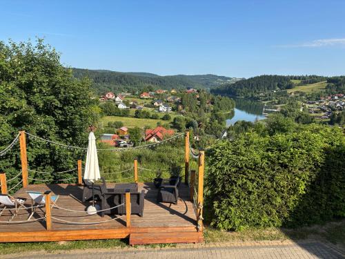 a wooden deck with chairs and an umbrella and a lake at Przystanek Berdo in Zawóz