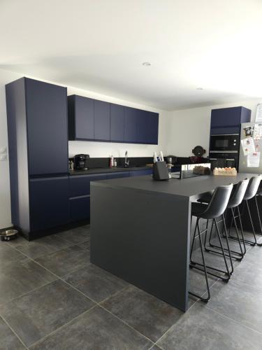 une cuisine avec des armoires bleues et un comptoir avec des chaises dans l'établissement Chez Florine - Maison Cosy, à Villemoustaussou