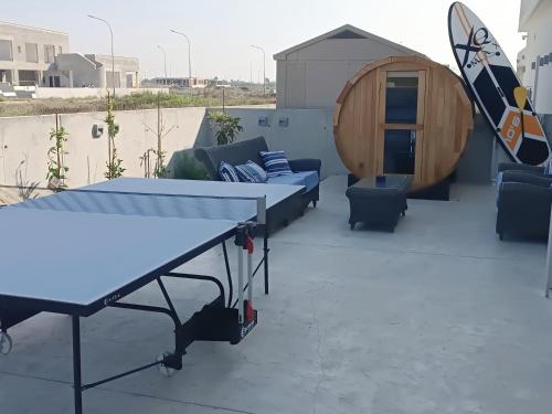 a ping pong table on a patio with a surfboard at Blue Aura Beach villa Larnaca in Pervolia