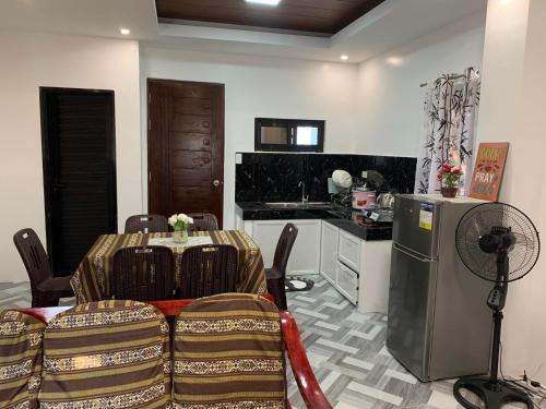 a room with a table and a kitchen with a refrigerator at 3Vhin Transient House in Sampong