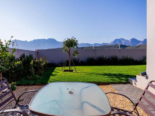 a glass table and chairs on a patio with a yard at Worcester the Karoo Guest Room in Worcester