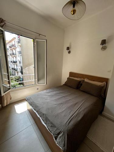 une chambre avec un lit et une grande fenêtre dans l'établissement charmant 2 pièces, à Nice