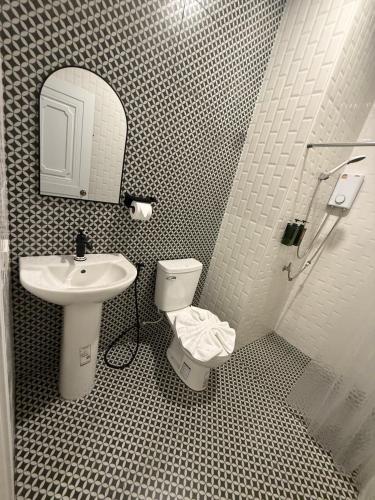 にあるNatcha Hotel and Residenceの洗面台、トイレ、鏡のあるバスルーム