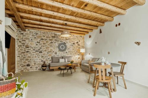 a living room with a stone wall and a table and chairs at St-Ten Stone Built Village in Áyioi Dhéka