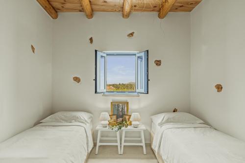 two beds in a white room with a window at St-Ten Stone Built Village in Áyioi Dhéka