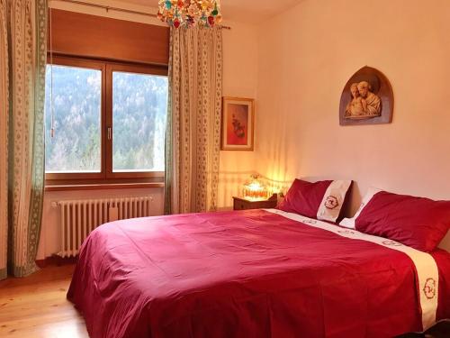 a bedroom with a large red bed with a window at Ciasa Marian 10 minutes from Cortina with free parking! in Borca di Cadore