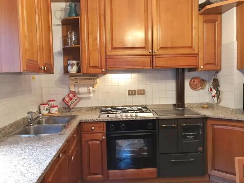 a kitchen with wooden cabinets and a black stove top oven at Ciasa Marian 10 minutes from Cortina with free parking! in Borca di Cadore