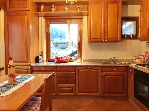 a kitchen with wooden cabinets and a table and a window at Ciasa Marian 10 minutes from Cortina with free parking! in Borca di Cadore