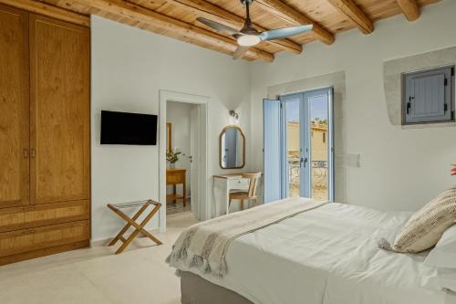 a white bedroom with a bed and a desk at St-Ten Stone Built Village in Áyioi Dhéka