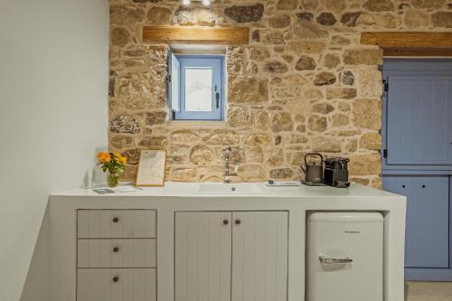 a kitchen with a sink and a stone wall at St-Ten Stone Built Village in Áyioi Dhéka