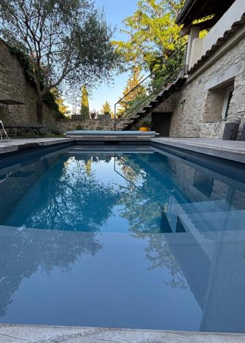 a swimming pool with a reflection in the water at Maison en pierres 6/8pers, piscine & sublime vue in Puygiron