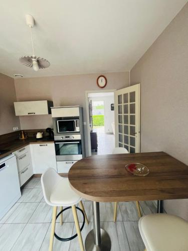 - une cuisine avec une table en bois et des chaises blanches dans l'établissement Maison située aux confins de la Vallée du Loir, au Lude