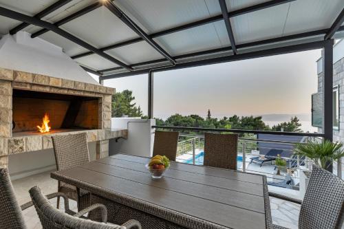 a patio with a wooden table and a fireplace at Villa la Perla in Baška Voda